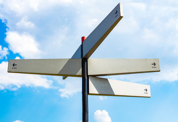 Blank signpost with many directions against blue sky in sunny day. Mockup. copy space
