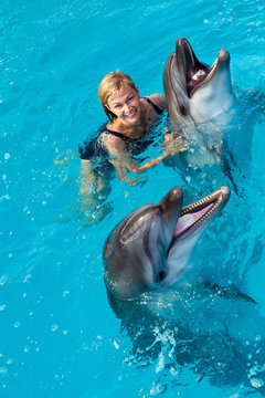Coach swims in the water with dolphins. Dolphin Assisted Therapy.