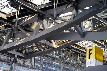 Check in counter F sign overhead, under steel structured roof, at the airport