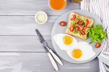Breakfast. Fried egg, vegetable salad and a grilled avocado sandwich on a grey background. Top view