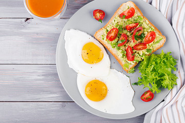 Breakfast. Fried egg, vegetable salad and a grilled avocado sandwich on a grey background. Top view