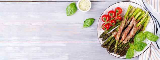 Grilled green asparagus wrapped with bacon on wooden table. Banner. Top view