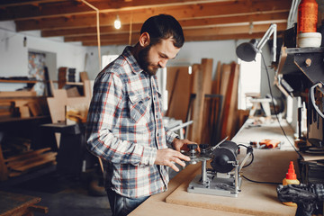 A man carves a tree. The carpenter works in a studio. An engineer provides a tree shape