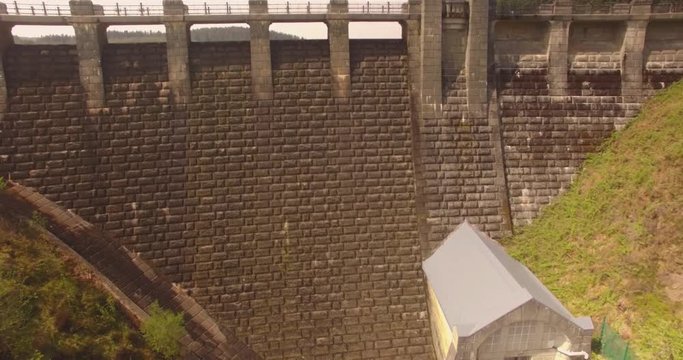 Rising shot up and over dam revealing huge reservoir and forests behind