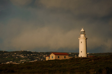 Fototapeta na wymiar Lighthouse and small building with town in background