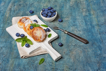 Cottage cheese pancakes with blueberries on white wooden board