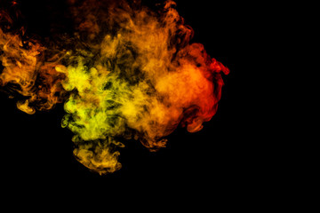 Beautiful horizontal column of smoke in the neon bright light of red, green, yellow and orange on a black background exhaled out of the vape. Nice pattern for printing and backdrop of colored waves.