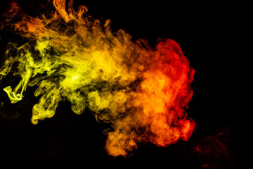 Beautiful horizontal column of smoke in the neon bright light of red, green, yellow and orange on a black background exhaled out of the vape. Nice pattern for printing and backdrop of colored waves.