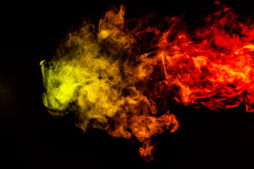 Beautiful horizontal column of smoke in the neon bright light of red, green, yellow and orange on a black background exhaled out of the vape. Nice pattern for printing and backdrop of colored waves.