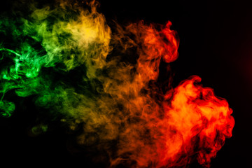 Beautiful horizontal column of smoke in the neon bright light of red, green, yellow and orange on a black background exhaled out of the vape. Nice pattern for printing and backdrop of colored waves.