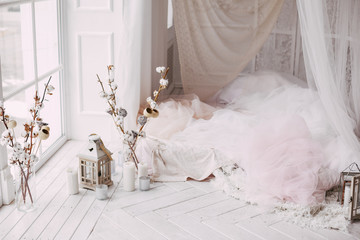 a large clean bright room with a window of white wooden floor, a mattress-bed, decorated with tulips curtains canopies, vases with cotton branches