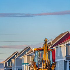 Clear Square Yellow loader parked on the road in front of houses under construction