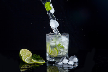 Summer cocktail mojito with splash on black background..