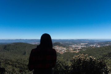 silhouette of a woman enjoying the scenic view from Doddabetta peak, highest peak in nilgiri district, forest reserve with the clear blue sky background. 