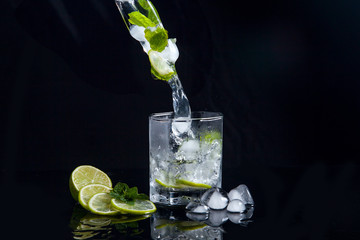 Summer cocktail mojito with splash on black background..