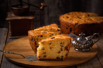Slices of home made cake with raisins on wooden plate and coffee grinder