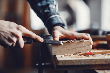 A man carves a tree. The carpenter works in a studio. An engineer provides a tree shape