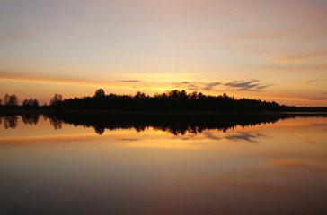 Fototapeta na wymiar Beautiful sunset on the forest lake. The sun is reflected in the water. Bright contrasting sky.