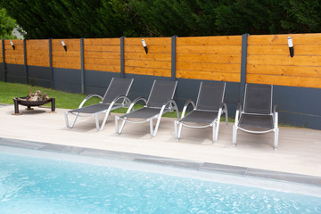Luxury Swimming Pool and bathe chair blue water in summer against grey wood wall