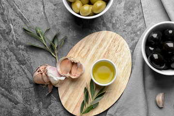 Tasty oil with olives and garlic on grey table