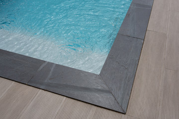 grey brown corner swimming pool detail with stairs and blue water