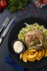 Boiled knuckle, served with cabbage and baked potatoes. Top view. Darkblue background. Dark mod.