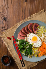 Korean beef with sprouts, spinach and fried egg.