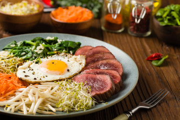 Korean beef with sprouts, spinach and fried egg.