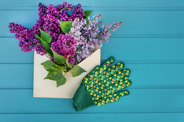 Purple flowers lilac in an envelope over wooden background	