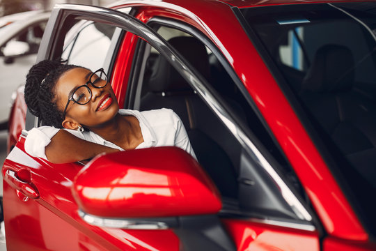 Woman buying the car. Lady in a car salon. Elegant black girl