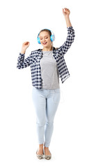 Beautiful young woman listening to music and dancing against white background