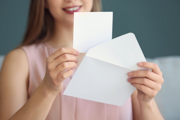 Young woman opening envelope with invitation at home, closeup