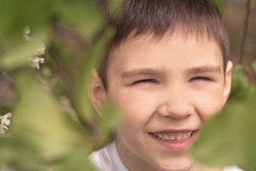 portrait of a laughing boy with brown eyes in the garden