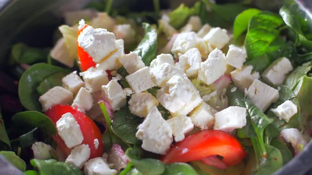 Feta cheese cubes fall on a fresh salad