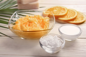 Bowl with body scrub and ingredients on table