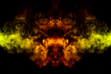 Smoke of different green, yellow, orange and red colors in the form of horror in the shape of the head, face and eye with wings on a black isolated background. Soul and ghost in mystical symbol
