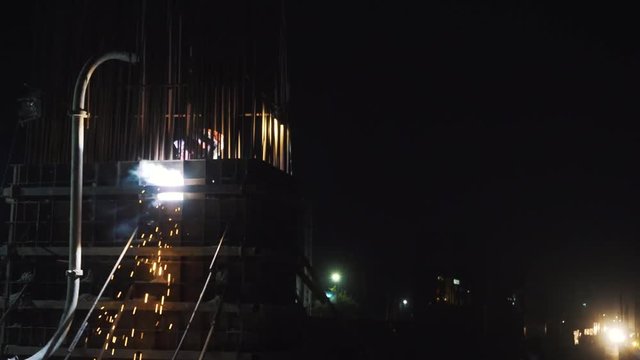 An industrial worker welding the metal structure for a flyover construction at night