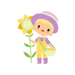 Cute Boy in Overalls, Rubber Boots and Hat Standing Next to Sunflower, Young Farmer Cartoon Character Engaged in Agricultural Activities Vector Illustration