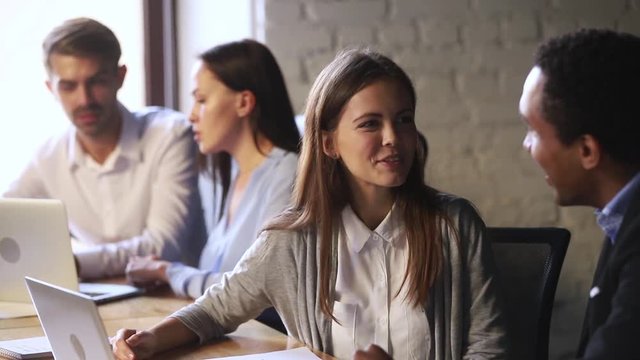 Friendly caucasian employee talking to african teammate laughing working together