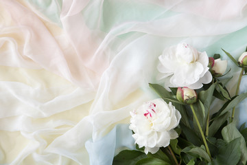 Flowers composition made of pink flowers and pastel scarf. Flat lay, top view, copy space