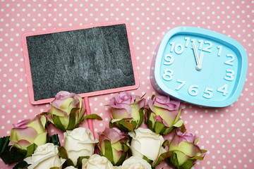 Blackboard and Alarm clock with roses flower decorate on pink polka dot background