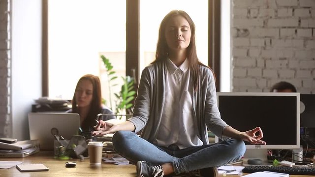 Calm businesswoman sit on office desk meditate manage work stress