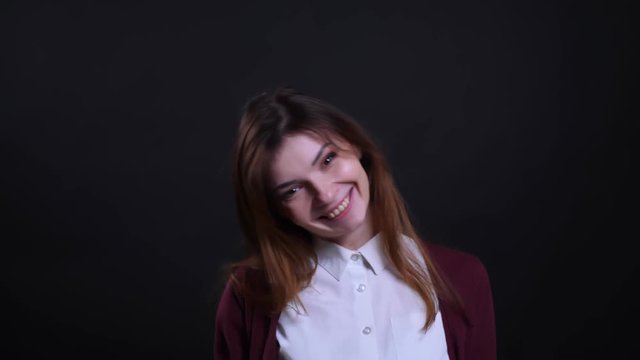 Portrait of young brunette businesswoman gets amused and show happiness into camera on black background.