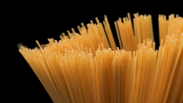 Raw spaghetti on black background slow motion.
