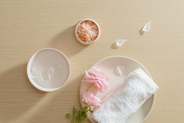 Spa setting of salt, towel, flower on plate on wood background with copy space. Relax. Close up. Top view.