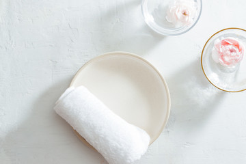 Spa setting with towel on plate and flowers on white background