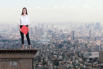 Beautiful businesswoman standing on the rooftop of a skyscraper over a city