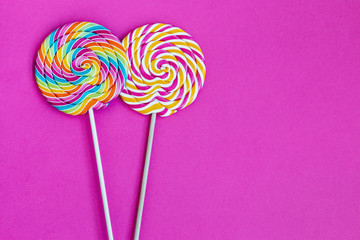 striped spiral multicolor Lollipop on pink background close up