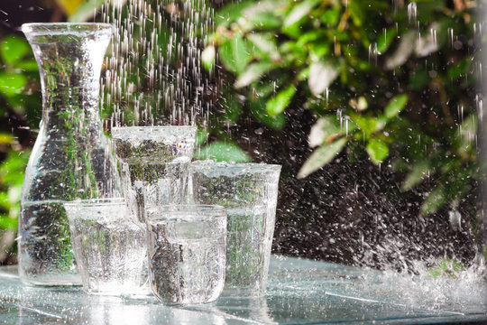 Glasses full of water for the refreshment on a hot summer day. Rain water on a table © boumenjapet