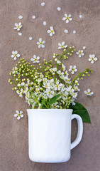 A bouquet of white flowers in a ceramic Cup on a concrete background flat lay